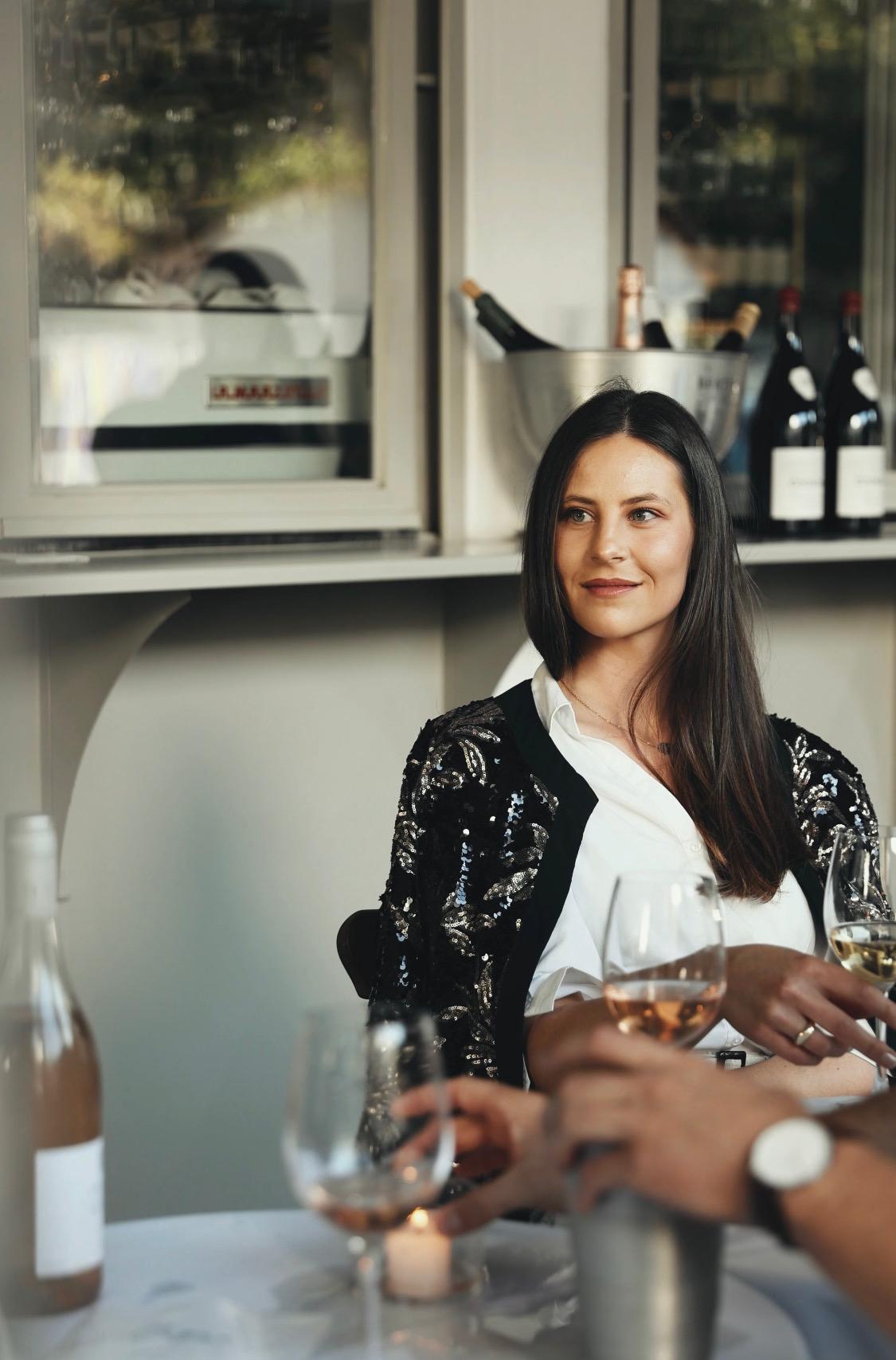 Claudia seated at a table with wine glasses at a Cape wine estate